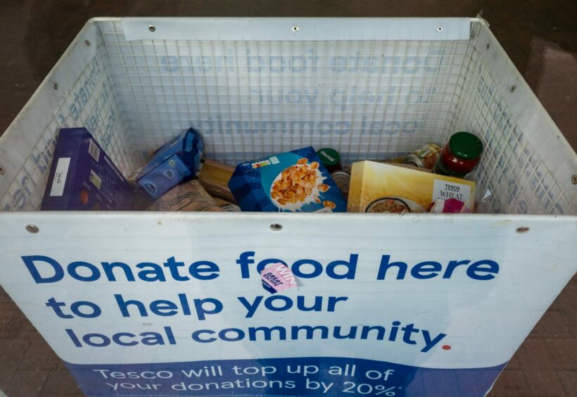 Photo shows a foodbank donations point at a supermarket, containing tins, jars and boxes of cereal.