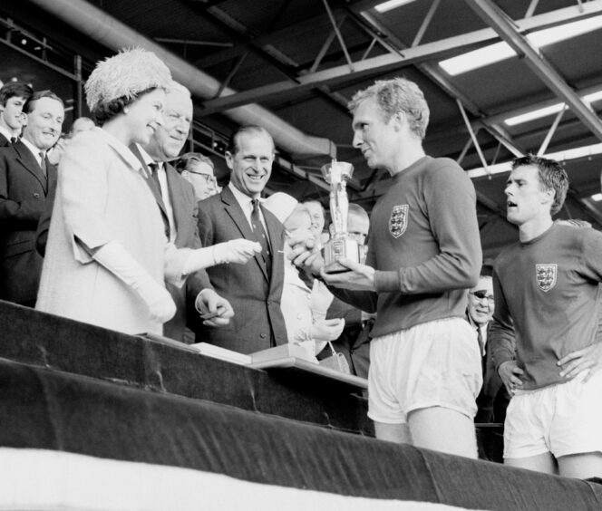 England captain Bobby Moore holds the Jules Rimet Trophy, collected from the Queen, after leading his team to a 4-2 victory over West Germany, in the 1966 World Cup final