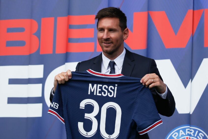 Lionel Messi holding a blue football shirt with 'Mess 30' on the back.