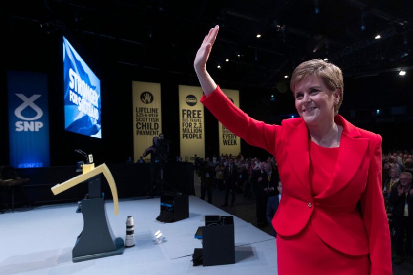 Photo shows Nicola Sturgeon waving from the stage of the SNP conference in Aberdeen.