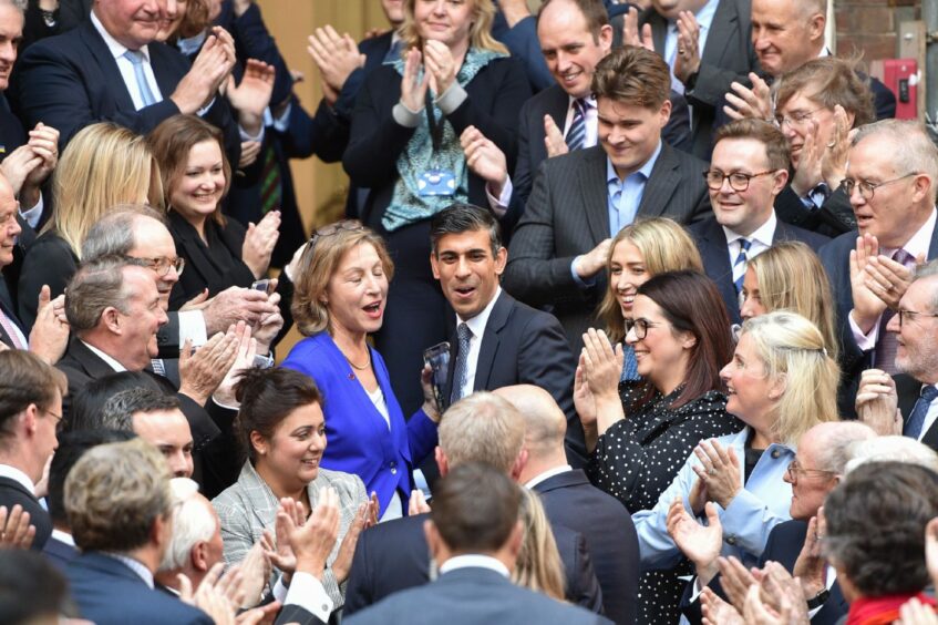 Photo shows Rishi Sunak being applauded by a large group of people.