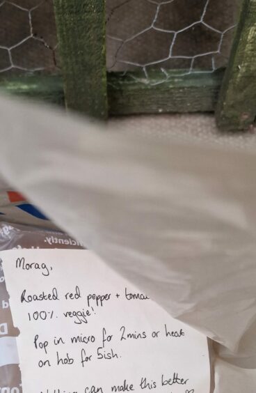 Photo shows an open shopping bag on the ground, revealing part of a note which reads: "Morag, Roasted red pepper and tomato, 100% veggie. Pop in micro for 2mins or heat on hob for 5ish."