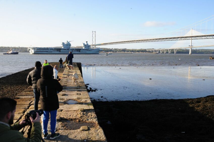 Crowds look on as the shop sails under the Forth Road Bridge in Fife