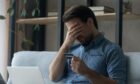 man looks upset as he sits with his credit card and laptop