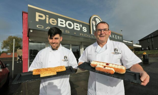 Gabriel Minott and Neill Elford holding footlong items outside Pie Bob's Bakery.