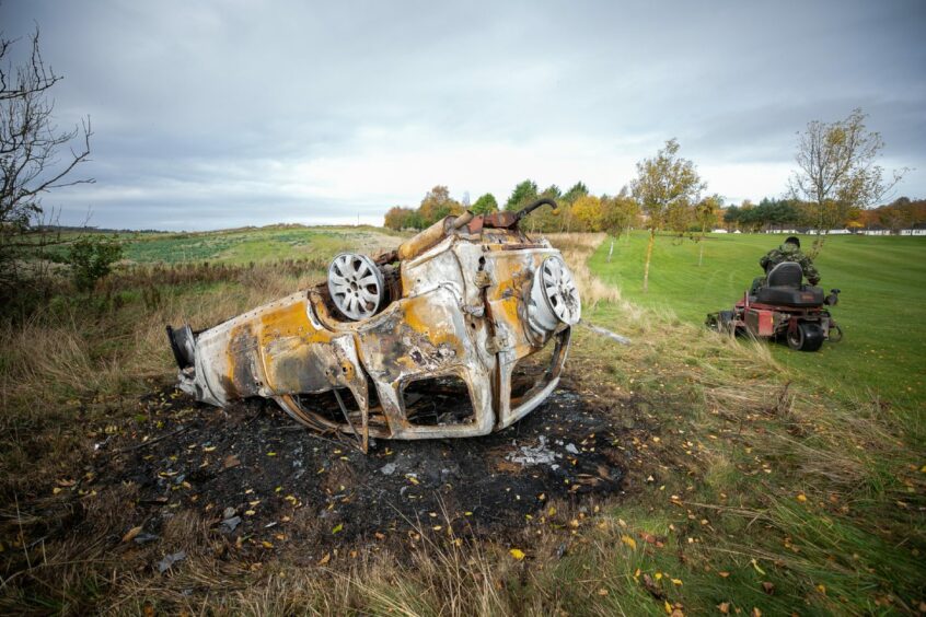The burnt out car is next to the sixth hole. 