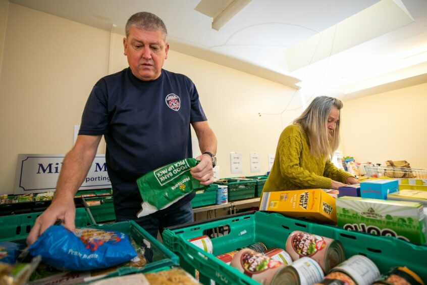 photo shows Jim Malone and Lynn McTaggart filling parcels at the Mill O' Mains Foodbank in Dundee.