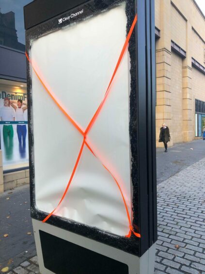 A damaged advertising hoarding outside the Overgate.