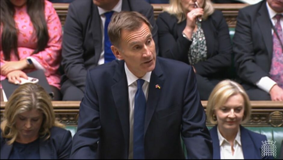 Photo shows Jeremy Hunt speaking in the House of Commons, flanked by Penny Mourdant and Liz Truss, who are both looking down.