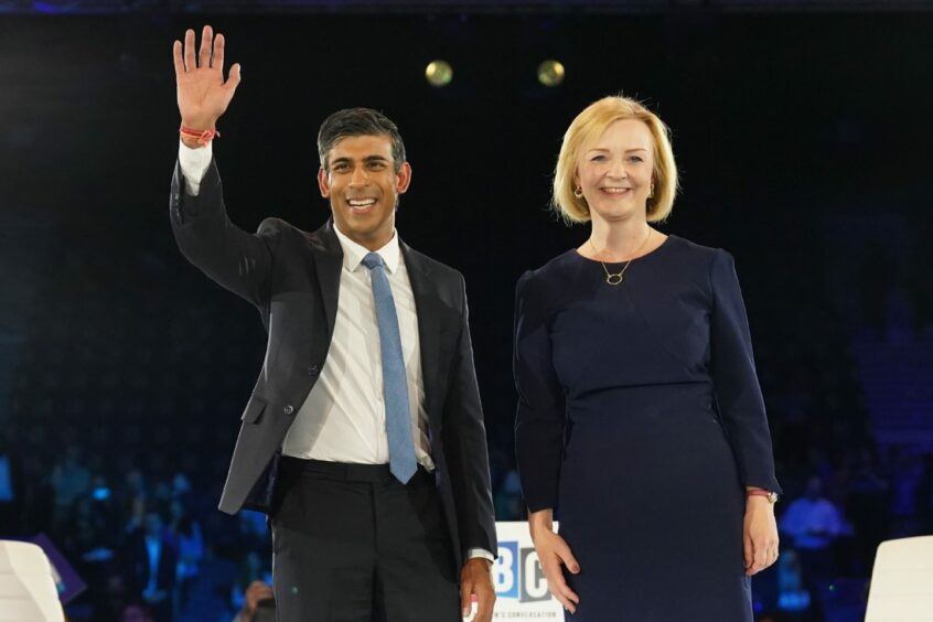 photo shows Rishi Sunak and Liz Truss standing side by side on a stage, smiling.