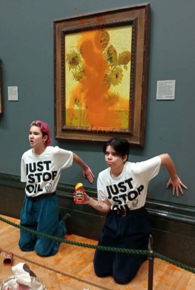 photo shows two protesters who have thrown tinned soup at Vincent Van Gogh's famous 1888 work Sunflowers at the National Gallery in London.