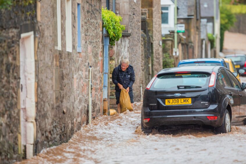 Local tries to stop flooding in Perthshire in September 2022 with sandbag.