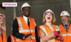 Photo shows Prime Minister Liz Truss and Chancellor of the Exchequer Kwasi Kwarteng in hard hats and high-visibility jackets laughing during a visit to a construction site in Birmingham