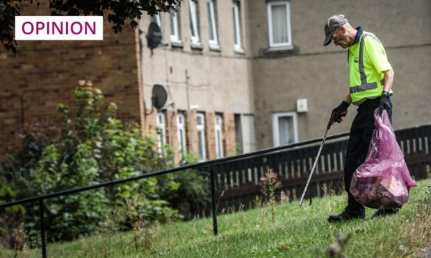 photo shows a council worker collecting waste in a Dundee housing estate.