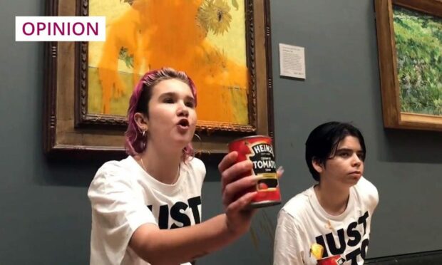 Photo shows two protesters in front of Van Gogh's Sunflowers painting in the National Gallery, London. Red soup is drippign down the painting and the two protesters are holding soup cans to the camera.