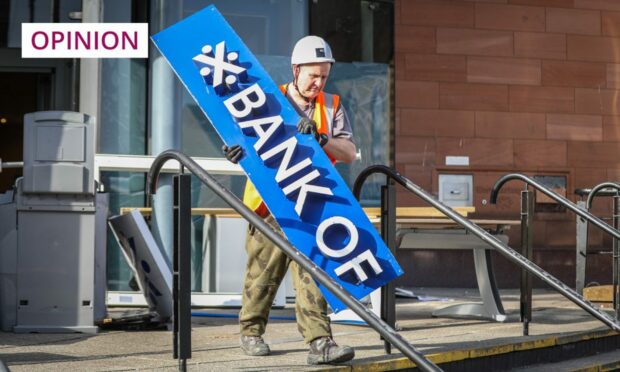 photo shows a worker in hard hat removing part of the Bank of Scotland sign from outside the former Nethergate branch in Dundee.