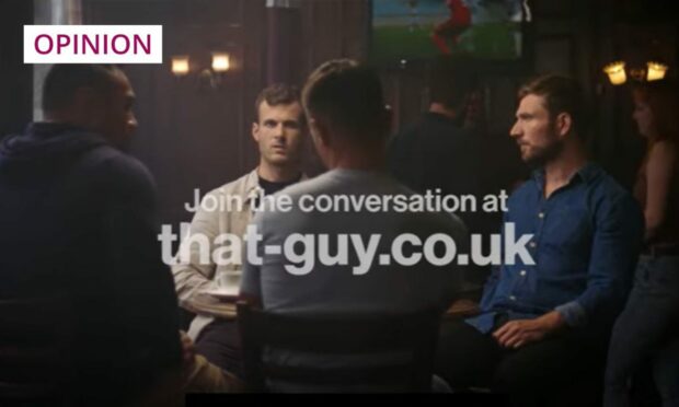 image shows a still from the 'That Guy' campaign video, featuring four young men sitting round a table in a bar.