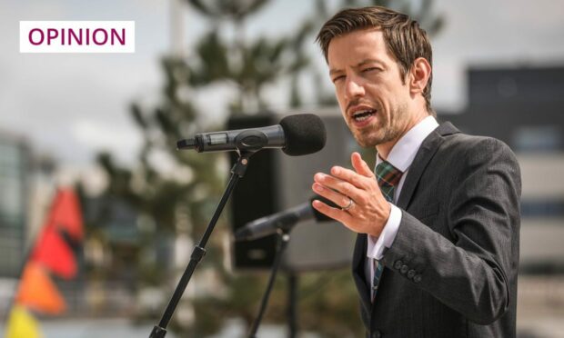 Photo shows Dundee City Council leader John Alexander speaking into a microphone at a public event.