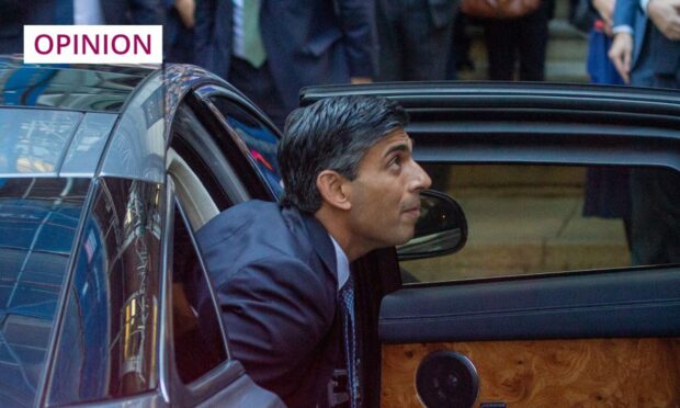 Photo shows Rishi Sunak looking up as he steps out of a luxury car.