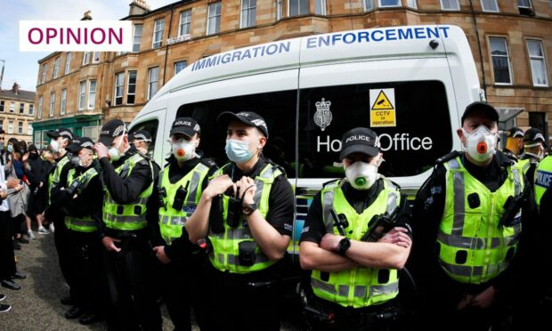 photo shows police officers circling a Home Office immigration enforcement van to protect it from protesters in Kenmure Street, Glasgow.