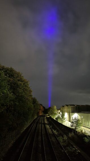 Blue lasers shoot into the sky from train.