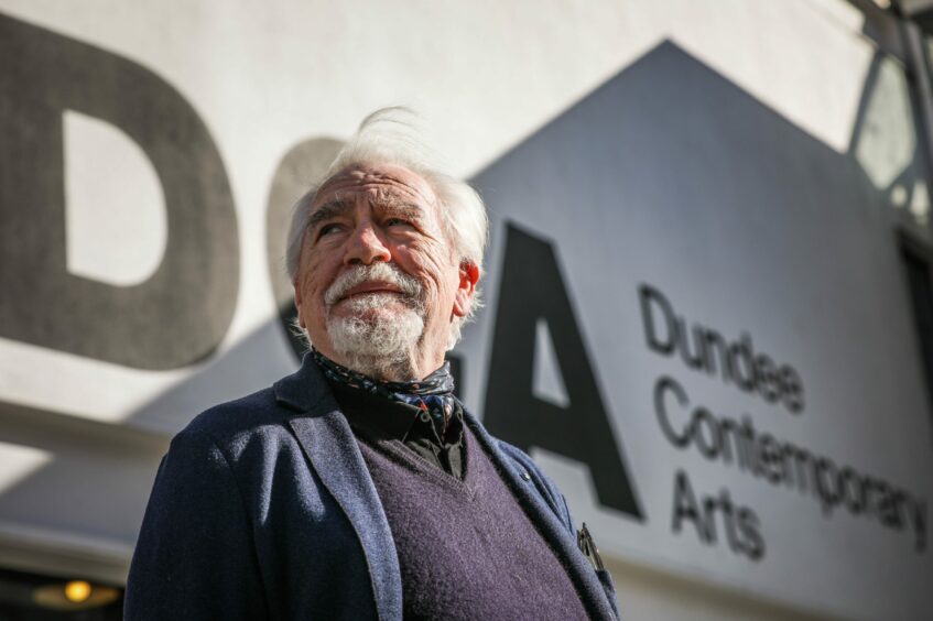 Photo shows actor Brian Cox outside the DCA, in front of a large sign saying Dundee Contemporary Arts.
