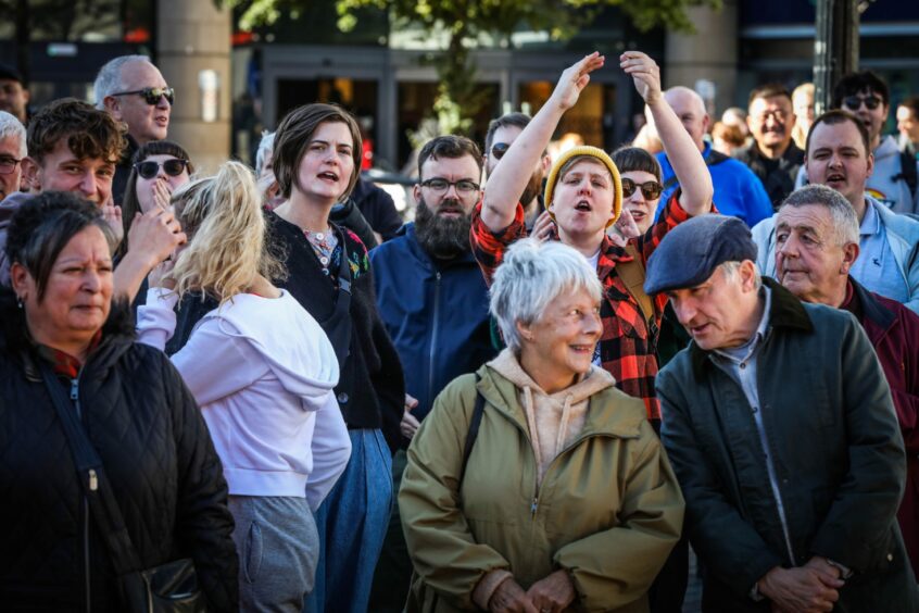 photo shows a large crowd of people of all ages gathered in the centre of Dundee for a protest.