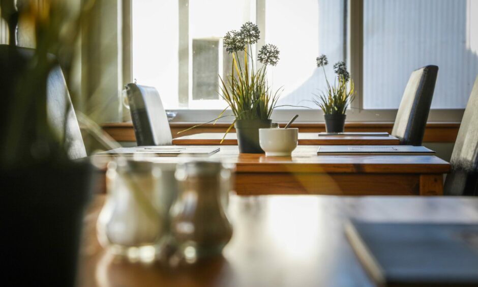 Tables inside the breakfast area at the Honeypot with flowers and menus on them.