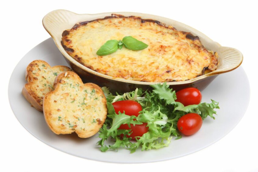 photo shows a dish of lasagne and garlic bread.