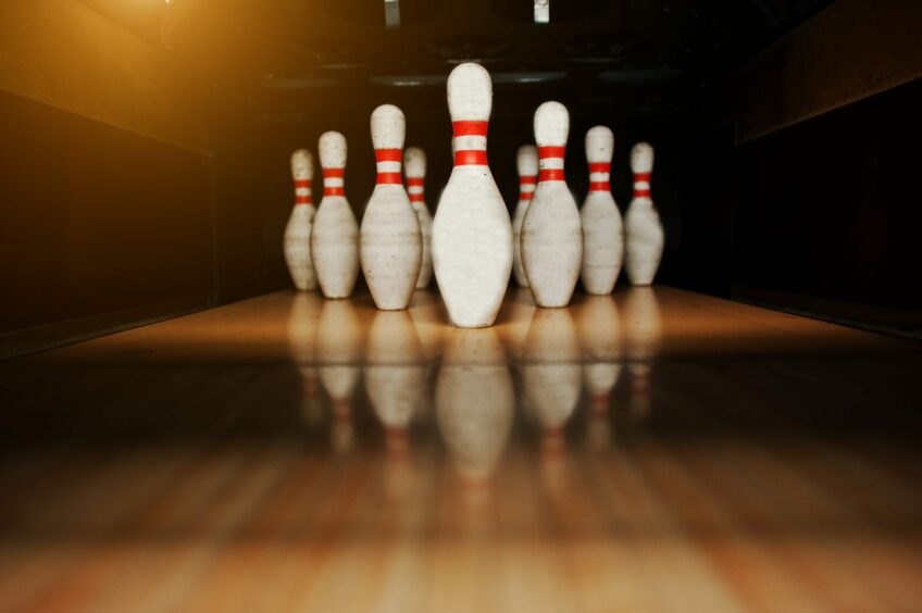 Photo shows 10 pins at the end of a tenpin bowling lane.