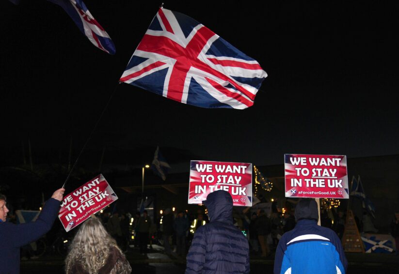 photo shows protesters waving Union Jacks and holding placards which read 'We want to stay in the UK'.