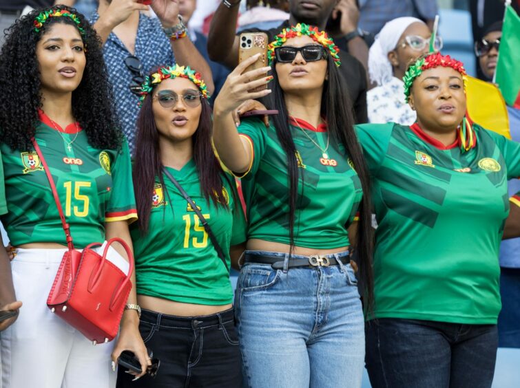photo shows four women in Cameroon shirts in the crowd for their country's game against Serbia.