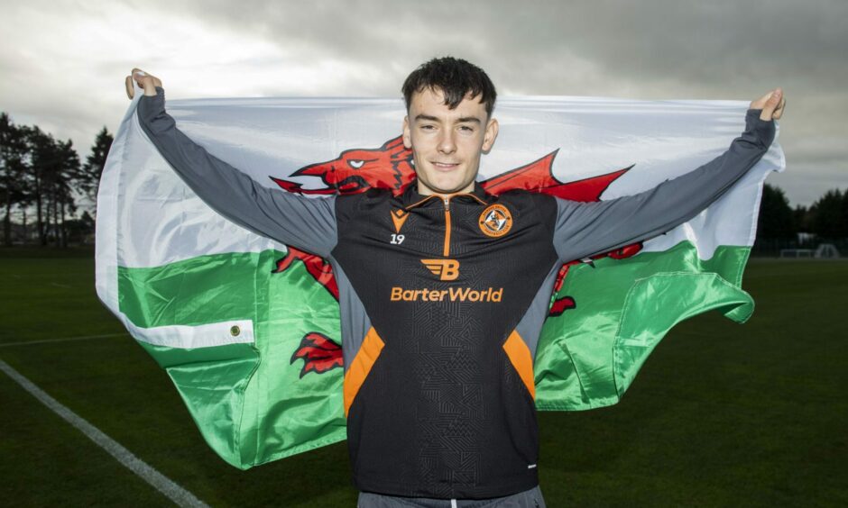 Dylan Levitt now of Hibs poses with the flag of Wales in St Andrews