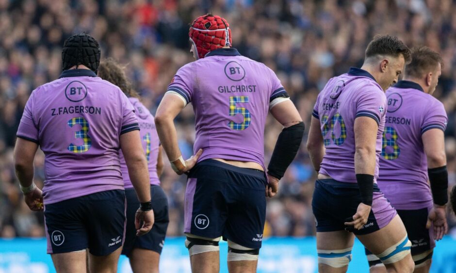photo shows Scotland rugby players from the back, wearing lilac tops with the numbers in Doddie Weir tartan
