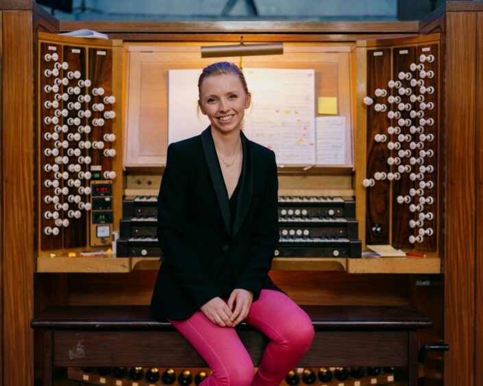 Anna Lapwood sitting down in front of an organ.