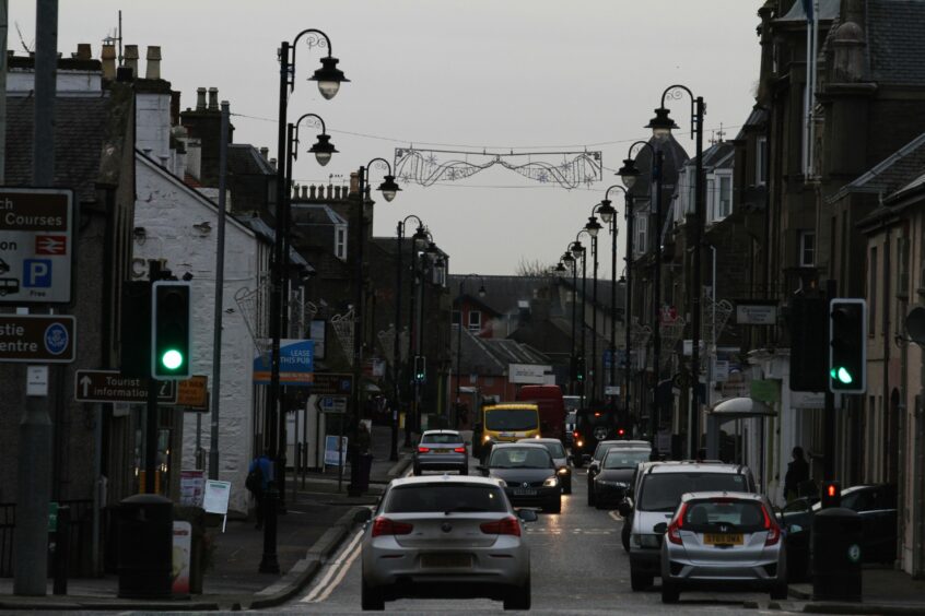 photo shows traffic on Carnoustie High Street with Christmas decorations strung from the lamp posts.