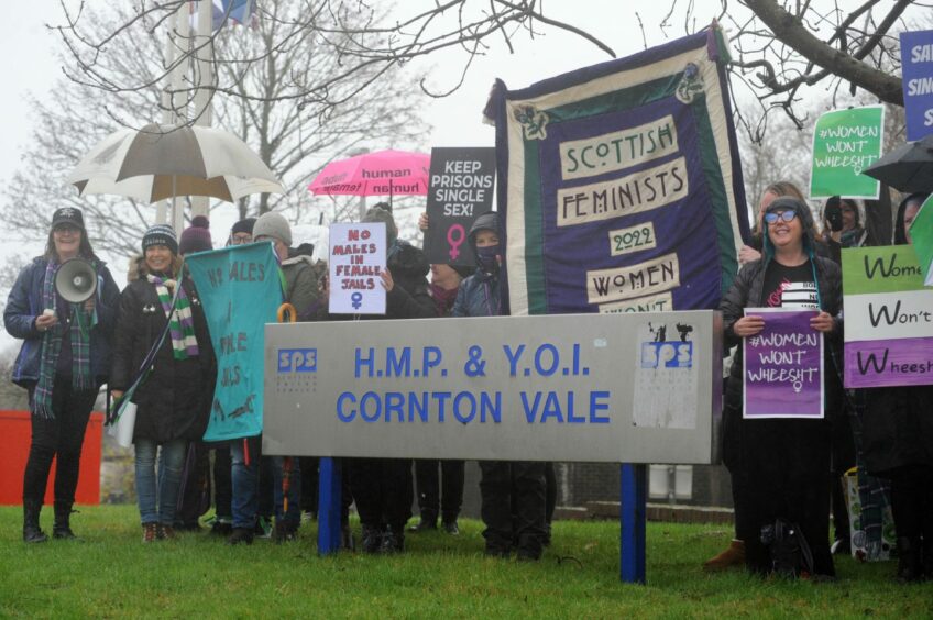 Group of women next to a sign for HMP Cornton Vale. They are holding placards with slogans such as 'No males in female jails'.
