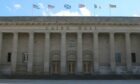 The Caird Hall with flags in the daytime.