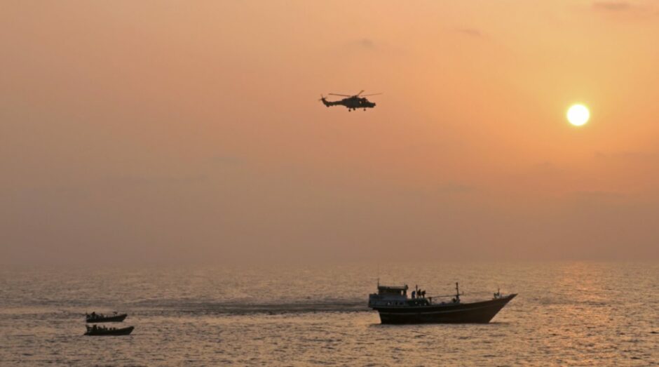 HMS Montrose crew and the ship's Wildcat helicopter about to board a drug-carrying dhow in the Gulf of Oman.