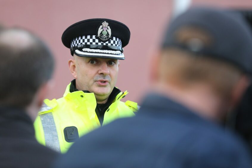 Chief Superintendent Phil Davidson in police hat and hi-vis jacket speaking to reporters in Dundee.