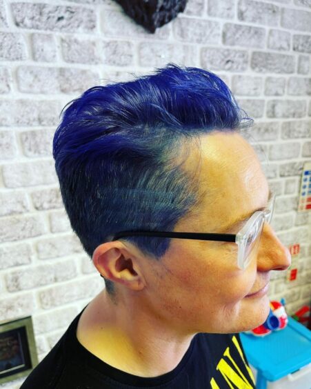 Photo shows Jacq Kelly with short, bright blue hair.