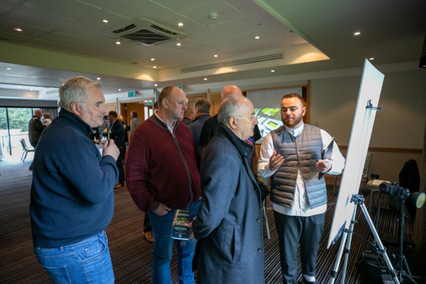 photo shows a group of men gathered round a whiteboard at a consultation event for Dundee FC's new stadium plans.