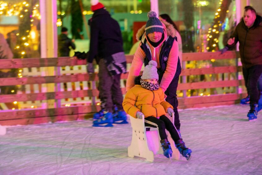 Photo shows a man and a young girl skating together on the ice rink in the centre of Dundee.