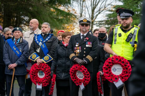 People holding wreaths at a remembrance day service in Kirkcaldy, Fife