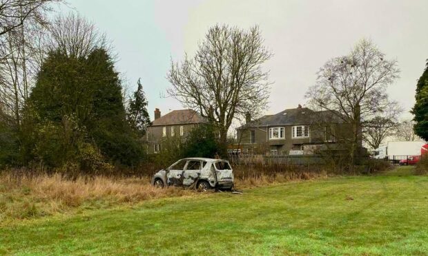 The burnt-out car on the rugby pitch near Forfar Road. Image: James Simpson/DC Thomson.