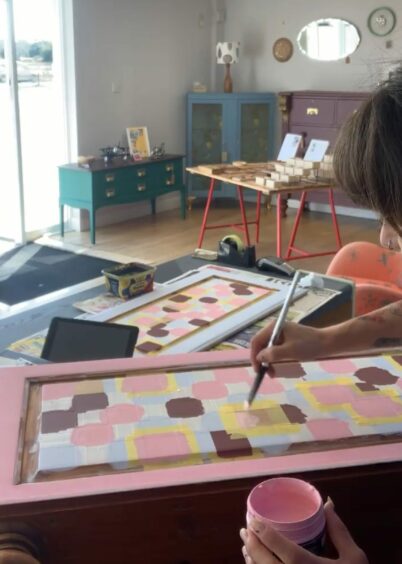 Diva Keith working on the checkerboard ottoman in the Tayside Upcycling &amp; Craft Centre. 