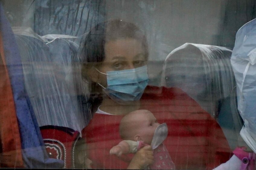 Photo shows a woman, thought to be a migrant, carrying a baby, aboard a coach in the Border Force compound in Dover, Kent.