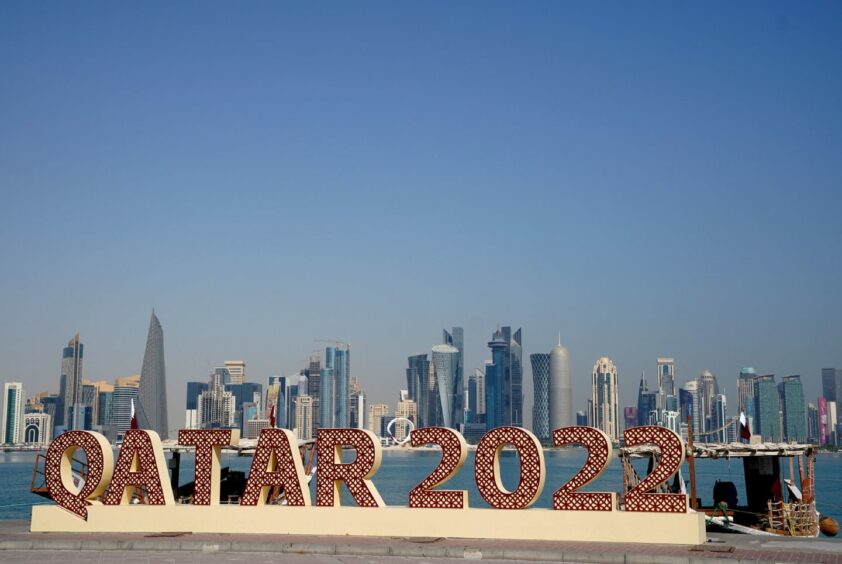 photo shows a sign for Qatar 2022 with the Dohar skyline behind.