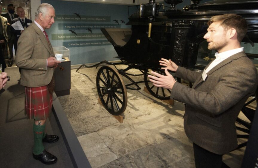photo shows Alistair Heather in front of an old carriage, talking to a kilted King Charles at the House of Dun.