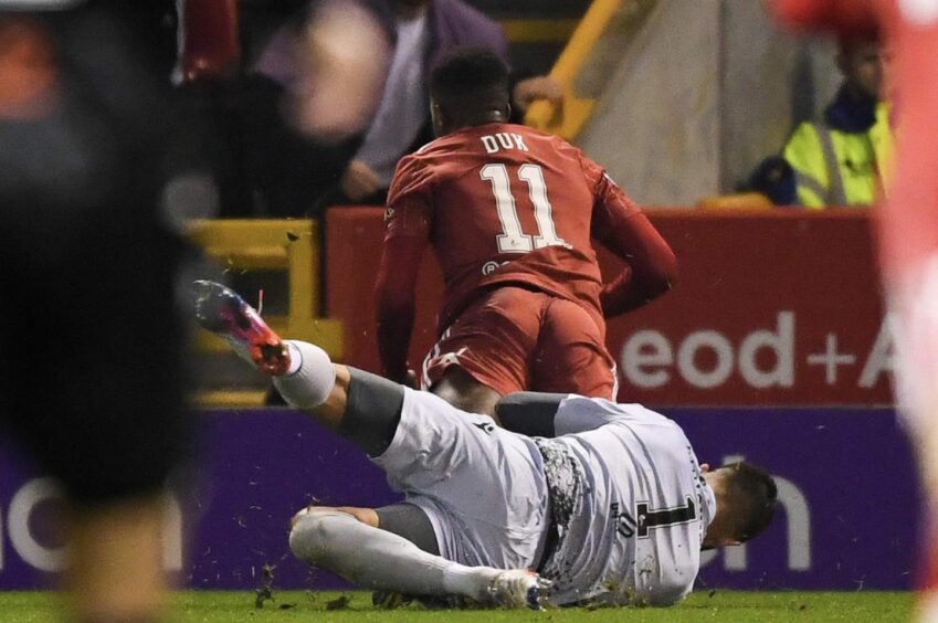 Dundee United goalkeeper Mark Birighitti concedes penalty by colliding with Aberdeen's Duk.